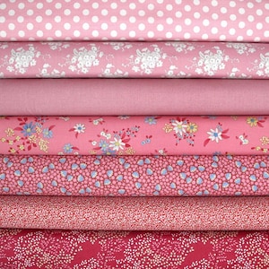 Può includere: Una pila di rotoli di tessuto rosa con vari motivi. I motivi includono pois bianchi, disegni floreali e piccole forme ripetute. I tessuti variano in tonalità, dal rosa chiaro al rosa intenso.
