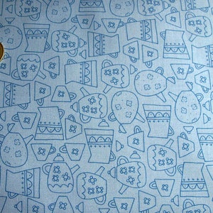 Könnte beinhalten: Ein blauer Stoff mit einem sich wiederholenden Muster aus Teekannen und Tassen in weißer Umrandung. Das Muster befindet sich auf einem hellblauen Hintergrund.