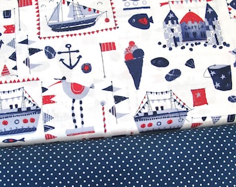 Op de afbeelding: Witte stof met een nautisch thema met rode, blauwe en witte illustraties van boten, ankers, vlaggen, ijshoorns, een meeuw en een zandkasteel. De stof is gelegd op een blauwe stof met witte stippen.