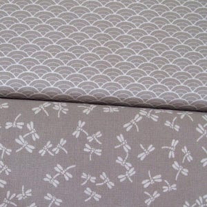 May include: Two pieces of fabric with a grey background. The top piece has a white pattern of overlapping half circles. The bottom piece has a white pattern of dragonflies.