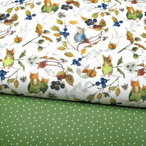May include: A white fabric featuring a repeating watercolour print of small mice wearing overalls, surrounded by blue berries, acorns, and green leaves, layered over a solid green fabric with a white polka dot pattern.
