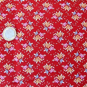 Könnte beinhalten: Roter Stoff mit einem sich wiederholenden Muster aus kleinen weißen Blüten mit rosa und blauen Akzenten.