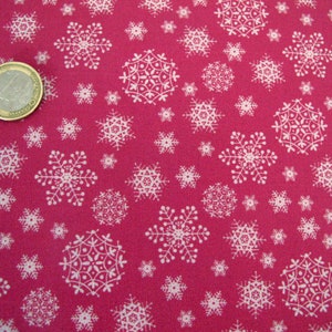 Könnte beinhalten: Ein Nahaufnahme eines pinkfarbenen Stoffes mit einem weißen Schneeflockenmuster. Der Stoff ist mit Schneeflocken in verschiedenen Größen bedeckt.