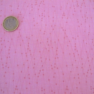 Könnte beinhalten: Hellrosa Stoff mit einem dezenten Punktmuster und einer Ein-Euro-Münze. Der Stoff hat ein zartes, strukturiertes Aussehen, wobei kleine Punkte und Linien ein geometrisches Design bilden. Die Münze ist goldfarben und liegt auf dem Stoff.