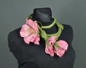 Puede incluir: Un collar de flores de fieltro rosa y verde. El collar está hecho de lana y es un accesorio único y elegante.
