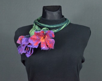 Puede incluir: Un collar de flores de fieltro con flores moradas, rojas y verdes. El collar está en un maniquí negro.