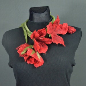 May include: A red felt flower necklace with green felt leaves. The necklace is displayed on a black mannequin.