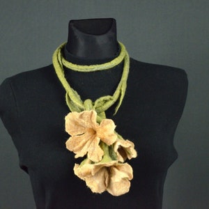 Peut inclure: Un collier en feutre vert avec un groupe de trois fleurs en feutre beige.
