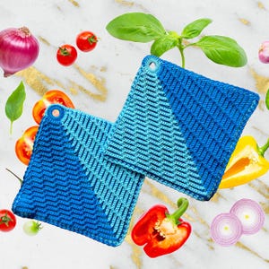 Könnte beinhalten: Zwei blaue und türkisfarbene gehäkelte Topflappen mit einem diagonalen Muster. Die Topflappen haben an jeder Ecke eine Schlaufe.