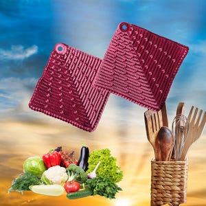 Könnte beinhalten: Zwei bordeauxfarbene Topflappen aus Häkelarbeit mit strukturiertem Design und Aufhängeschlaufe. Die Topflappen werden mit einer Sammlung von Küchenutensilien aus Holz in einem geflochtenen Korb und frischem Gemüse präsentiert.