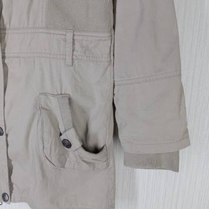 Peut inclure: Une veste beige avec un panneau en velours c&ocirc;tel&eacute; sur le devant et une fermeture &agrave; boutons. La veste a une poche sur le c&ocirc;t&eacute; gauche et une manchette c&ocirc;tel&eacute;e sur la manche droite.
