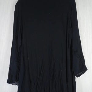 Op de afbeelding: Zwart top met lange mouwen en een asymmetrische zoom. Het kledingstuk is gemaakt van een lichte stof en hangt aan een houten hanger. De mouwen hebben een uitlopend ontwerp en de algehele stijl is los en relaxed.