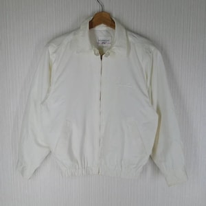 May include: Off-white Givenchy Sport jacket with a full-length zipper, collar, and elasticized waist. The jacket has a small logo on the chest and the Givenchy Sport label on the collar. The jacket is hanging on a wooden hanger.