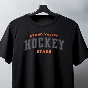 May include: Black t-shirt with the text "GRAND VALLEY HOCKEY STARS" in orange and gray lettering.