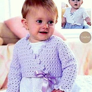 May include: A light purple crocheted baby cardigan with a tie closure. The cardigan is shown on a baby wearing a white dress.