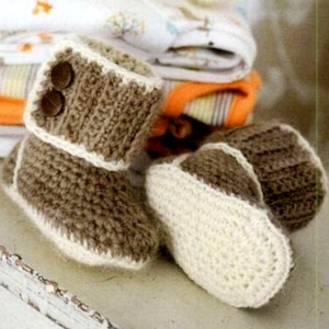 May include: A pair of brown knitted baby booties with white trim. The booties have a fold-over cuff and are made with a soft, textured yarn.