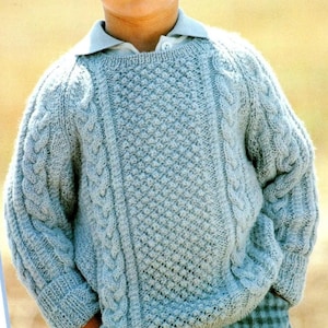Könnte beinhalten: Ein hellblauer Strickpullover mit einem Zopfmuster und einem strukturierten Stichdesign.