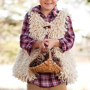 May include: A child wearing a cream-colored, shaggy vest over a red and black plaid shirt, holding a small woven basket filled with pinecones. The vest has a button closure. The child is smiling.
