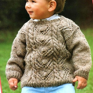 May include: A brown knitted sweater with a cable knit pattern. The sweater has a round neckline and long sleeves.