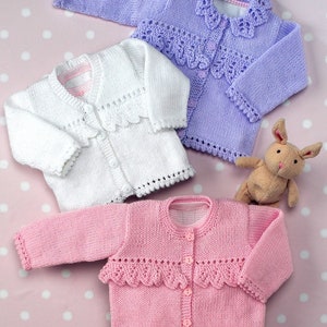 May include: Three knitted baby cardigans in pink, white and lavender with a crocheted lace trim around the collar and bottom. The cardigans have button fastenings.