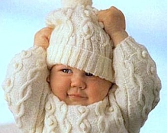 May include: A white knitted baby sweater and hat set with a cable knit pattern and a pom pom on the hat.