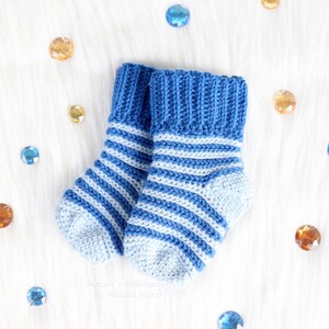 May include: A pair of blue and white striped knitted baby socks with a blue ribbed cuff.