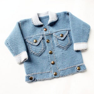 Puede incluir: Una chaqueta vaquera de punto azul con cuello y puños de punto blanco. La chaqueta tiene cierre de botones y dos bolsillos con costuras decorativas.