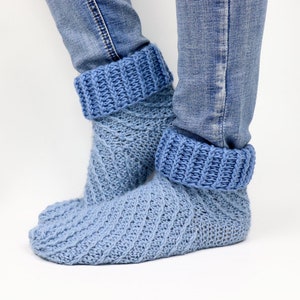Könnte beinhalten: Ein Paar blaue Strick-Hausschuhe mit geripptem Bund. Die Socken sind aus einem Farbverlaufsgarn gefertigt, das von einem dunkleren Blau zu einem helleren Blau übergeht.