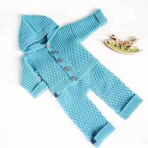 May include: A light blue knitted baby onesie with a hood and button closure. The onesie has a textured knit pattern.
