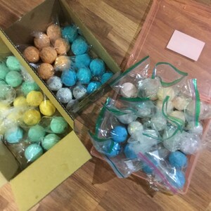 May include: Assortment of colorful, spherical craft supplies, packaged in clear plastic bags and cardboard boxes. The colors include shades of blue, green, yellow, and orange. Some are in a pink plastic container.