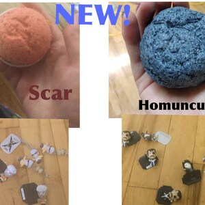 May include: The image showcases a collection of items. One is a round, orange bath bomb labeled "Scar." Another is a blue, textured bath bomb called "Homunculi." There are also small figurines and charms scattered on a wooden surface. The word "NEW!" is displayed.