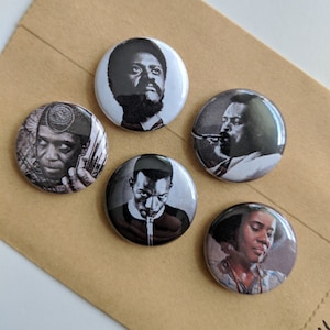 May include: Set of five black and white button badges featuring portraits of musicians. Each badge features a different musician with a unique expression and pose.