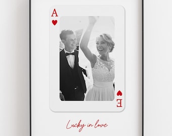 May include: A framed wall print featuring a large playing card design with a black and white photograph of a couple in formal wedding attire. The card displays a red letter A and heart symbol, with the red cursive text Lucky in love below.