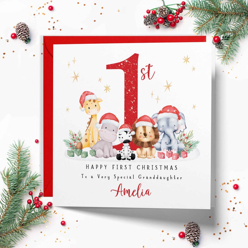 Op de afbeelding: Een vierkante kerstkaart met een groot rood cijfer 1st, omringd door aquarelillustraties van een giraf, nijlpaard, zebra, leeuw en olifant met kerstmutsen. Tekst: HAPPY FIRST CHRISTMAS To a Very Special Granddaughter Amelia.