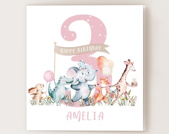 May include: A pink and white birthday card featuring a large pink number 3, surrounded by stars. The number 3 is decorated with a banner that reads "Happy Birthday". There are animals on the card, including a rabbit, a crocodile, an elephant, a fox, and a giraffe. The card is personalised with the name "Amelia".