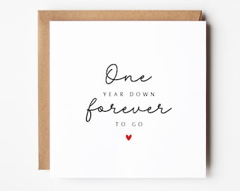 May include: A white card with black text that reads "One year down forever to go" with a small red heart below the text.