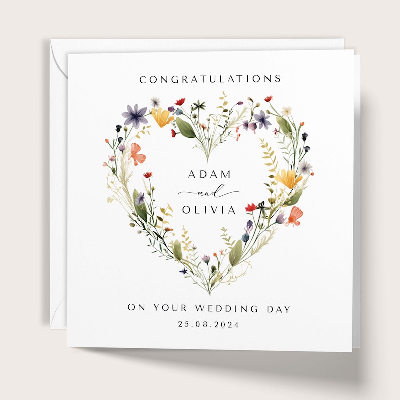 May include: A white wedding card featuring a heart-shaped floral wreath. The card displays the words "Congratulations", the names "Adam and Olivia", and the date 25.08.2024, with the message "On Your Wedding Day" at the bottom.