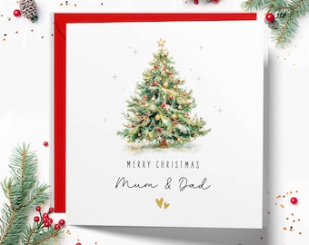 May include: A square Christmas card with a red border and a white interior. The card features a watercolour illustration of a decorated Christmas tree. The text "MERRY CHRISTMAS Mum & Dad" is written below the tree, with two gold hearts.