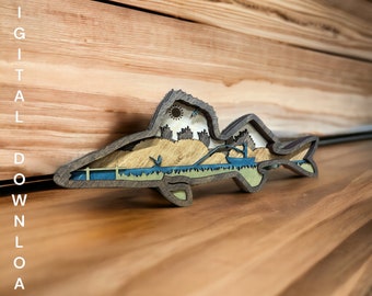 May include: A wooden cutout of a fish with a detailed scene inside. The fish is brown, blue, and green. The scene inside the fish includes a sun, trees, and a fishing rod. The text "SVG Digital Download" is at the bottom of the image.