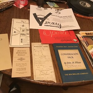 May include: A collection of vintage books and pamphlets on a wooden table. The books include "Memories" by Thomas Barber, "Jamestown, Williamsburg, Yorktown", "Warranty Deed", "Opera", "Conversación Fácil" by John M. Piltaro, and a stack of pamphlets with the word "Bread" on the cover.