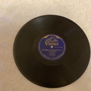 May include: A black vinyl record with a blue label. The label features the Victor logo and the text "Will Rogers Nominates Henry Ford for President Will Rogers 45369-A".