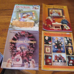 May include: Four colourful craft project books with titles "Snowman Cottage", "Krackerjack", "Sunshine Cottage", and "Across From The Prairie". Each book features a different winter-themed design.