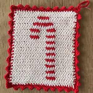 May include: White crocheted pot holder with a red crocheted border and a red candy cane design in the center.