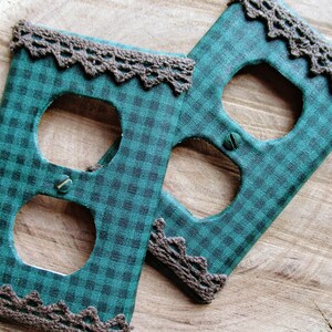 May include: Two green and black checkered outlet covers with brown lace trim.