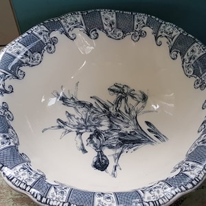 May include: A large white ceramic bowl with a blue and white floral design. The bowl has a scalloped edge and a decorative border.