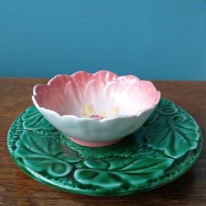 May include: A vintage floral-patterned ceramic dish with a green leaf design. The dish is made of white ceramic with pink and yellow floral accents. The dish is perfect for serving snacks or desserts.