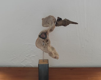 May include: A wooden sculpture of a bird with a long, thin beak. The sculpture is mounted on a black wooden base.