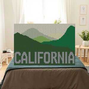 May include: A cross-stitch pattern of a green mountain landscape with the word "CALIFORNIA" in gray letters at the bottom.