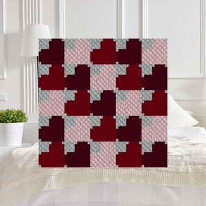 May include: A crochet blanket with a checkerboard pattern of red, pink, and gray hearts.