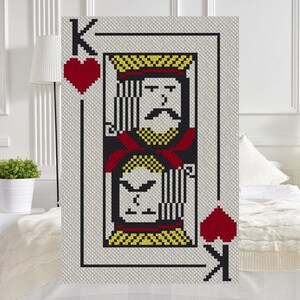 May include: A crochet blanket featuring a King of Hearts playing card design. The card is red, yellow, and black with a white background. The King's face is depicted in a pixelated style.